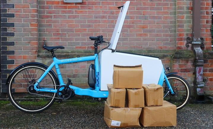 Blue electric delivery bike beside six cardboard boxes
